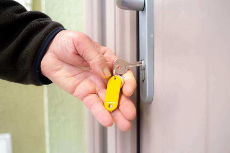 Hand unlocking a front door with a key on a yellow fob